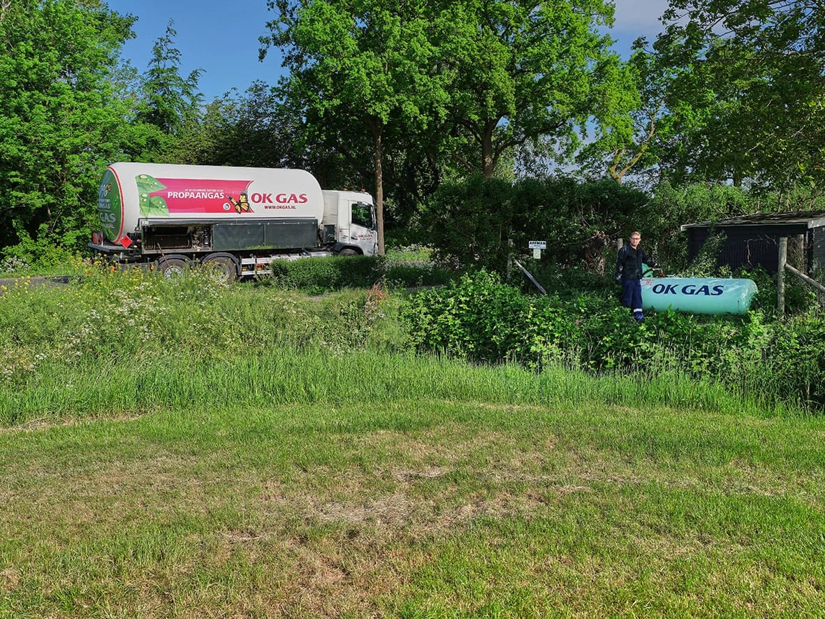 Een tankwagen rijdt langs een propaangastank bij iemand in de tuin